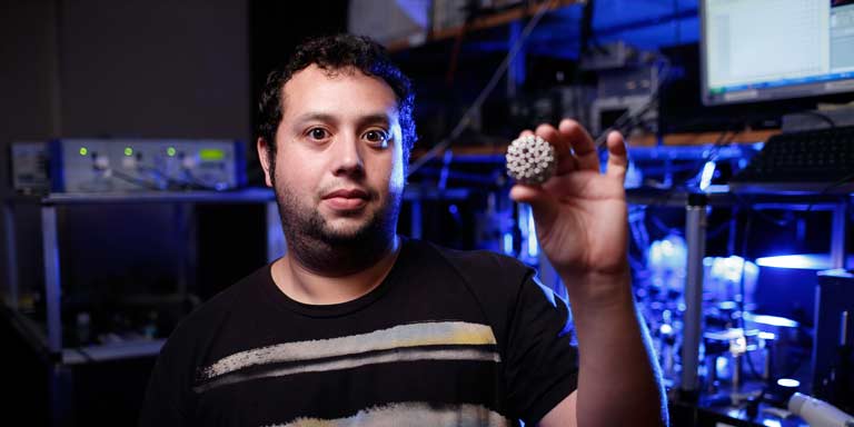 A man holding up a small model of a particle
